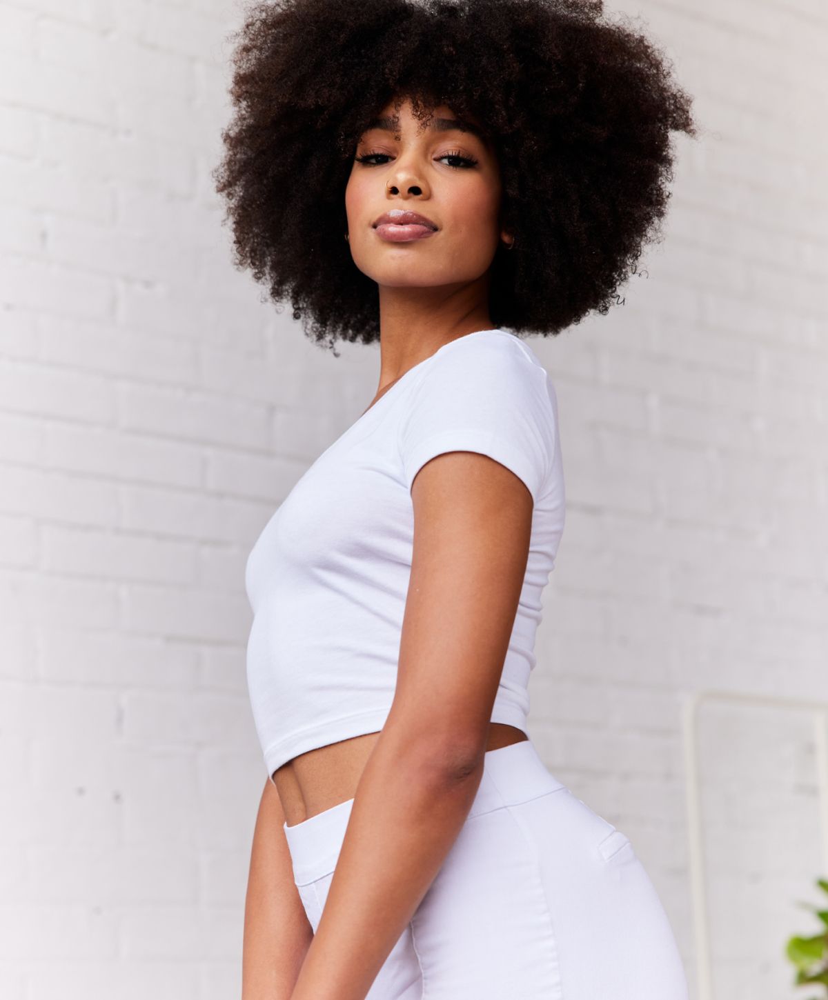Model with curly hair in white outfit.
