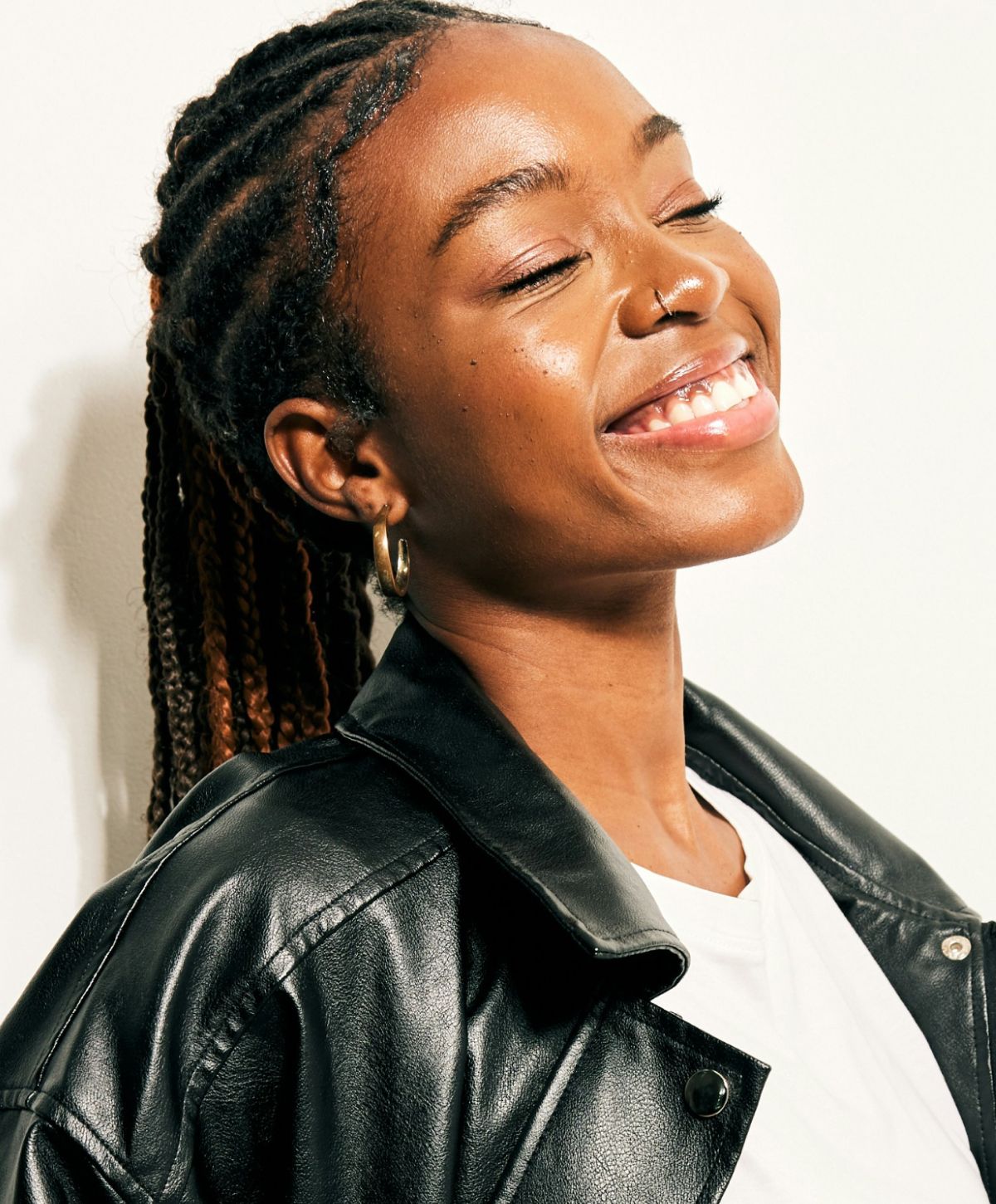 Smiling woman with braided hair in leather jacket.