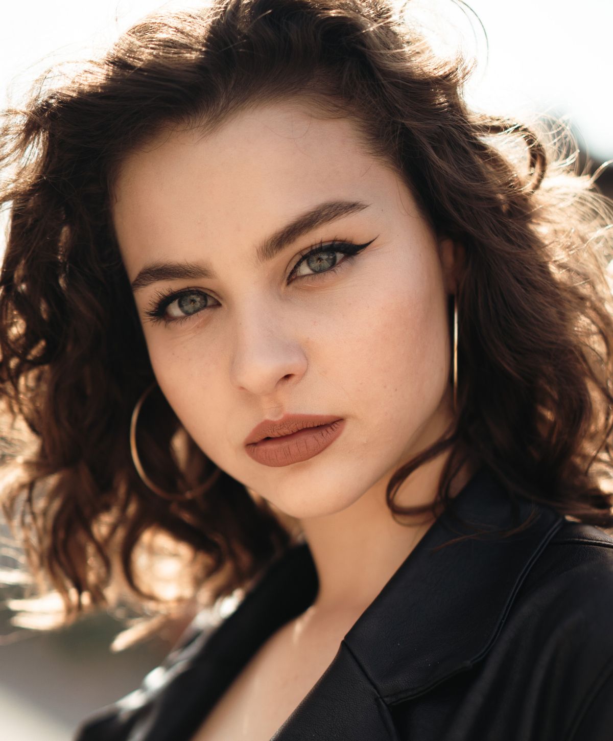 Portrait of a woman with curly hair and makeup.