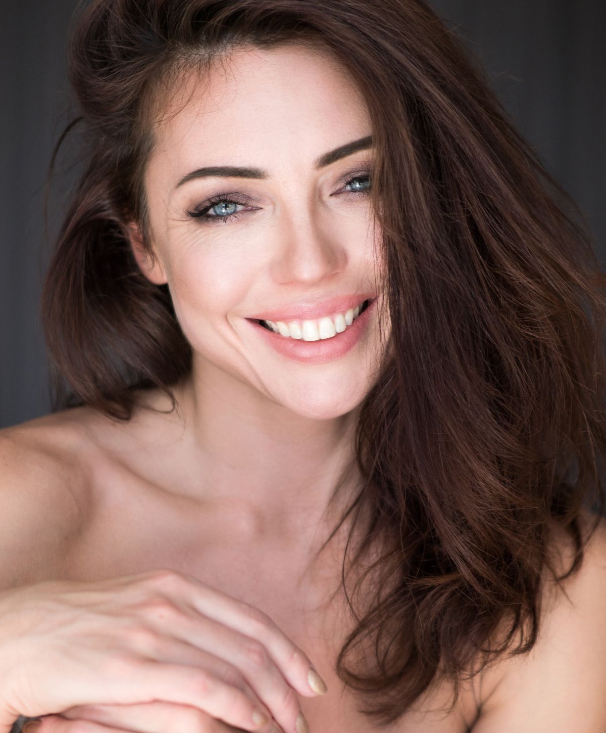 Smiling woman with long brown hair, natural lighting.