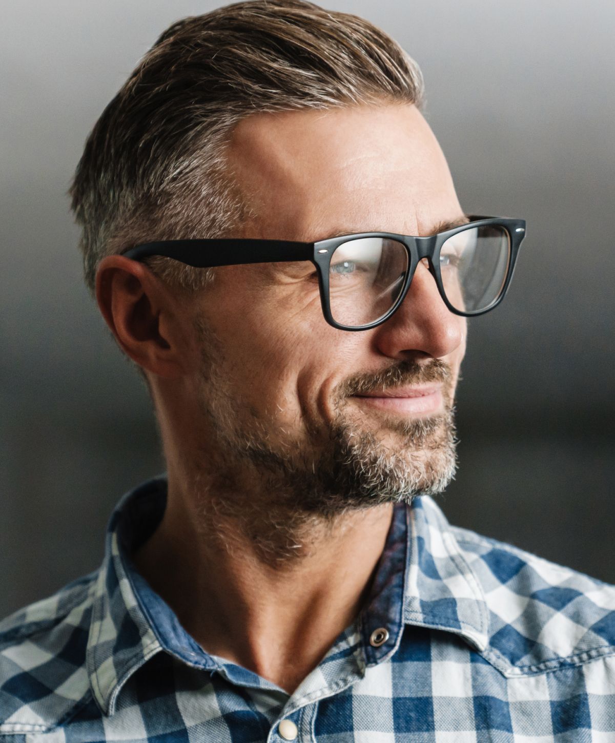 Man with glasses and plaid shirt smiling.