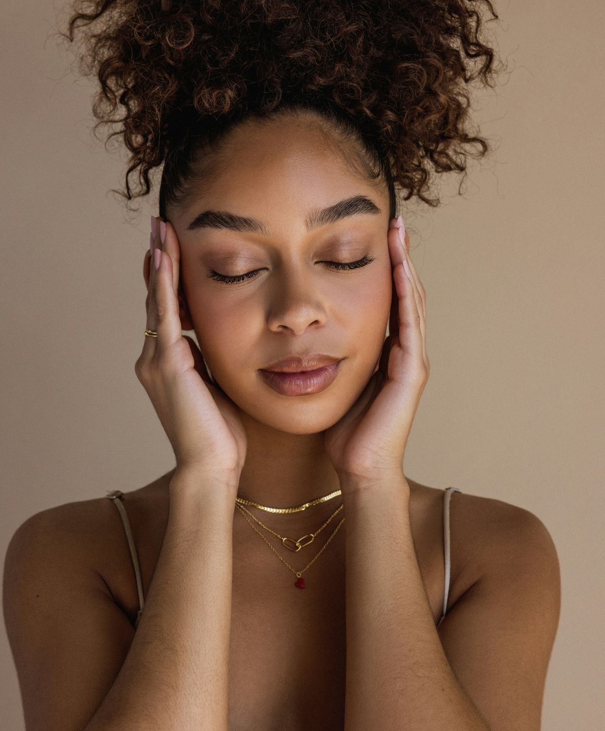 Woman with curly hair, eyes closed, serene expression.
