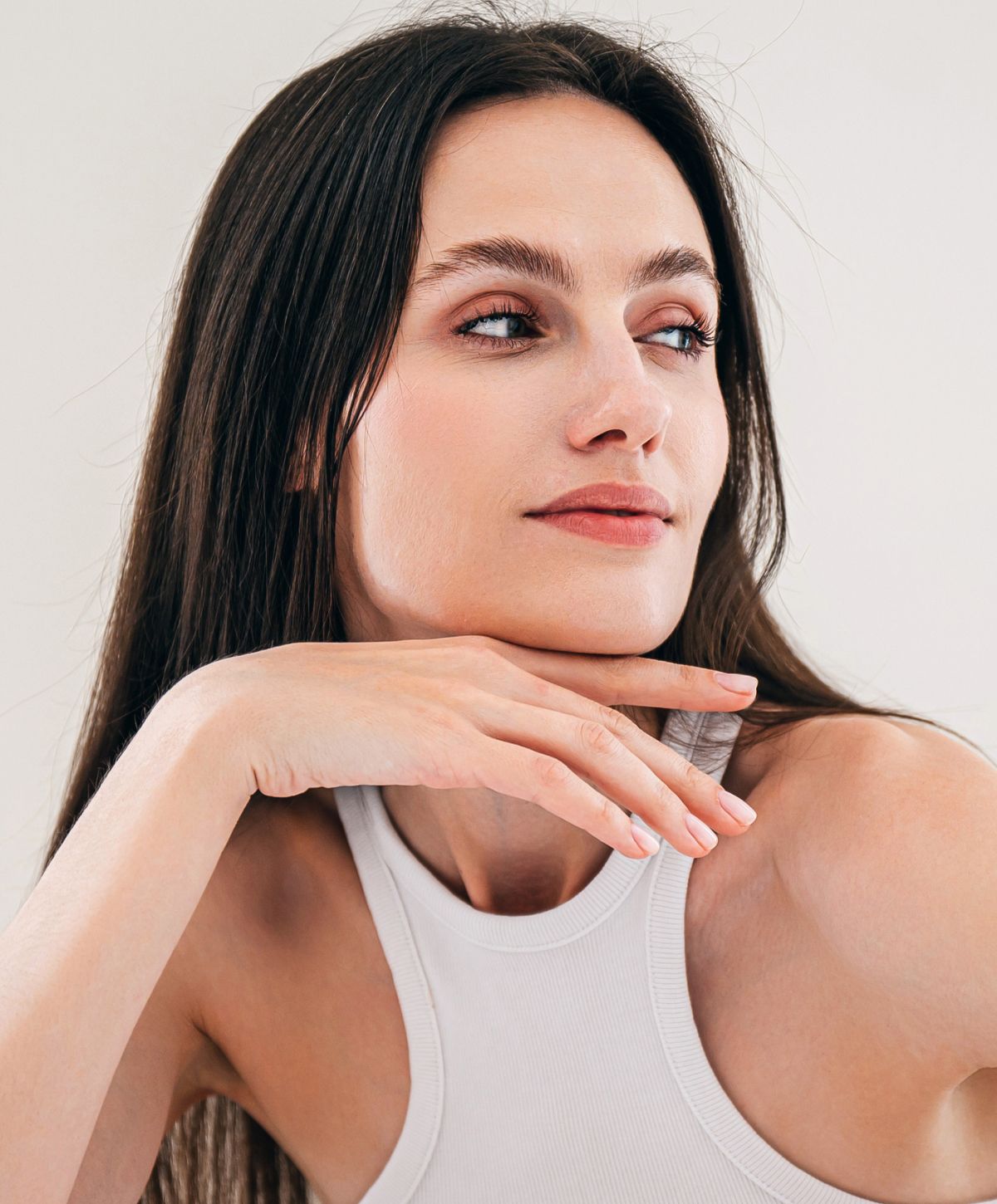 Woman with long hair resting chin on hand.