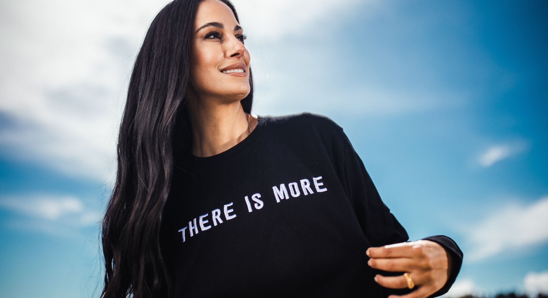 Woman in sweatshirt under bright blue sky.