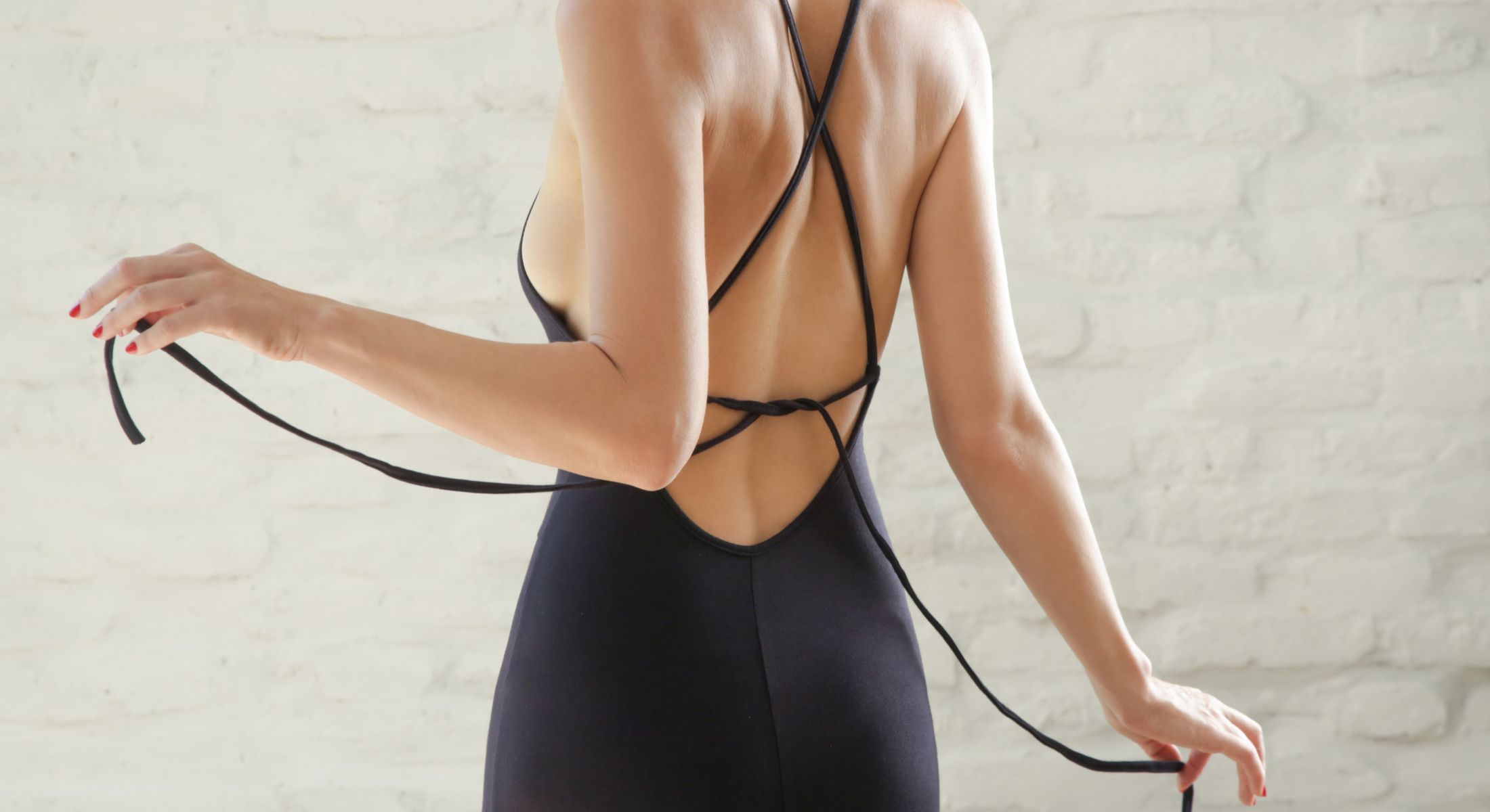 Woman tying black straps on a dress.