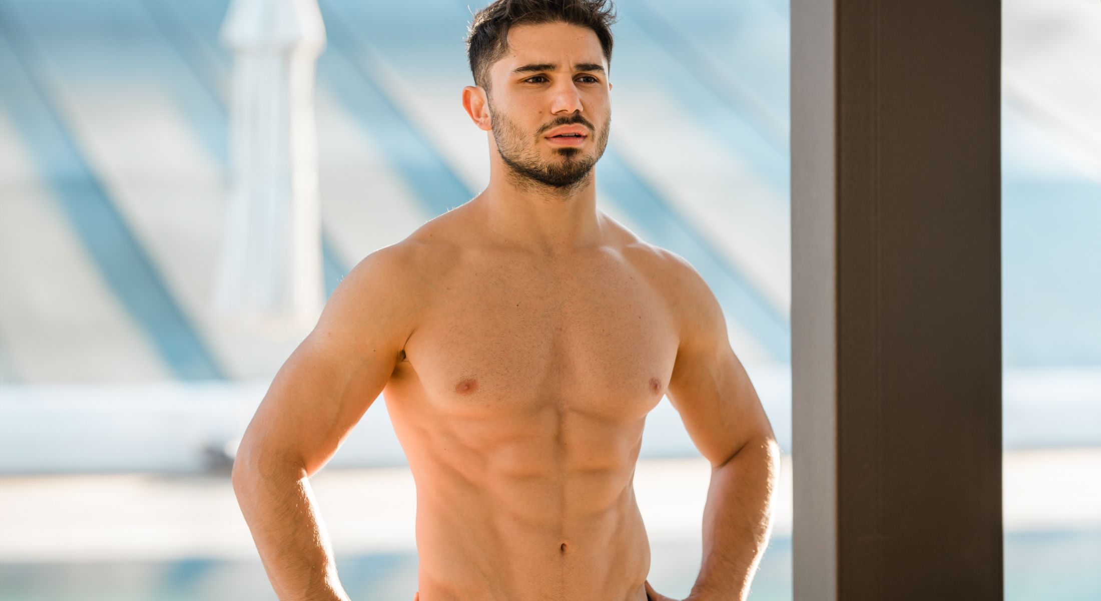 Fitness model posing outdoors, showing muscular physique.