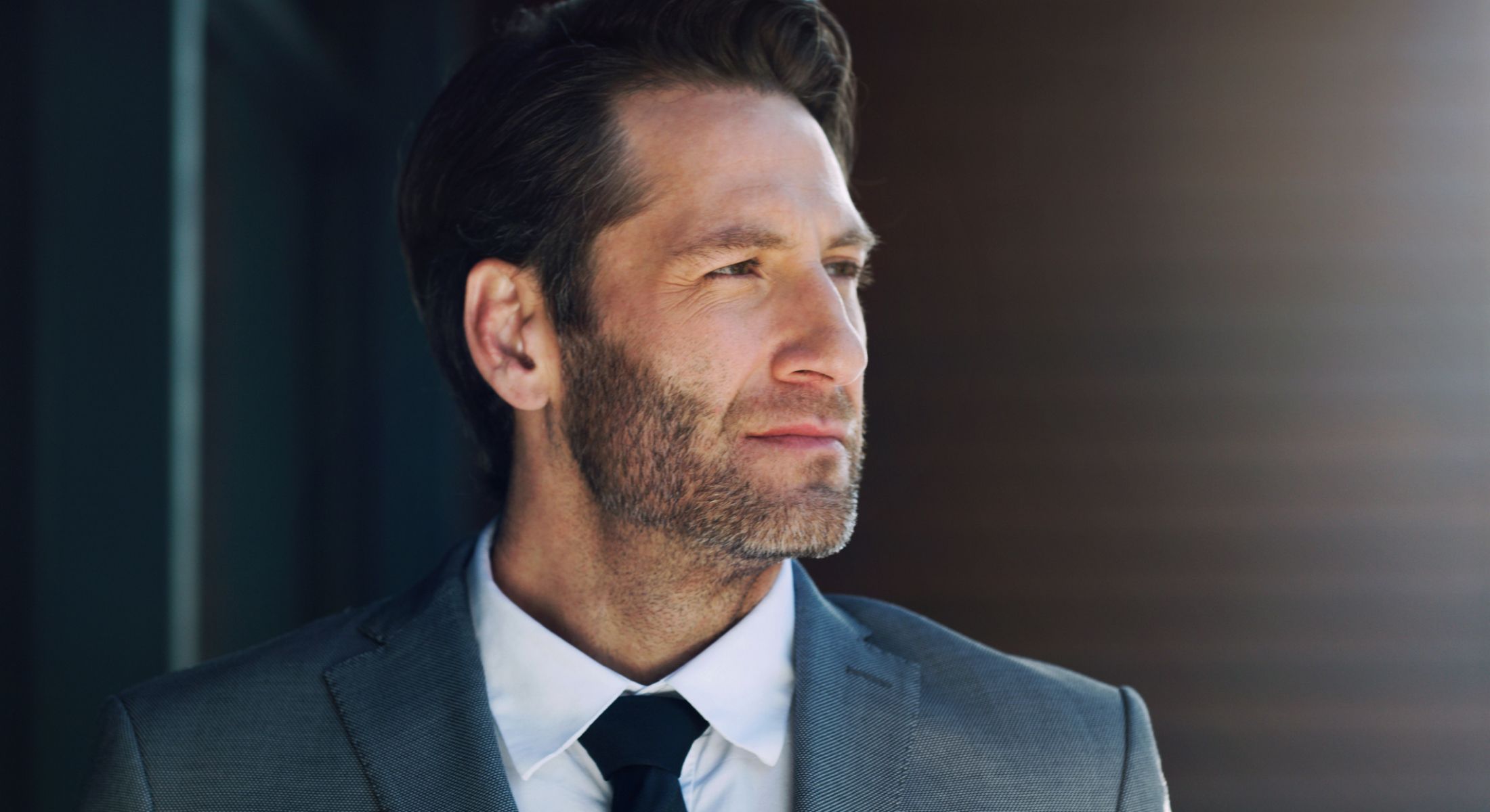 Man in suit looking thoughtfully away from camera.