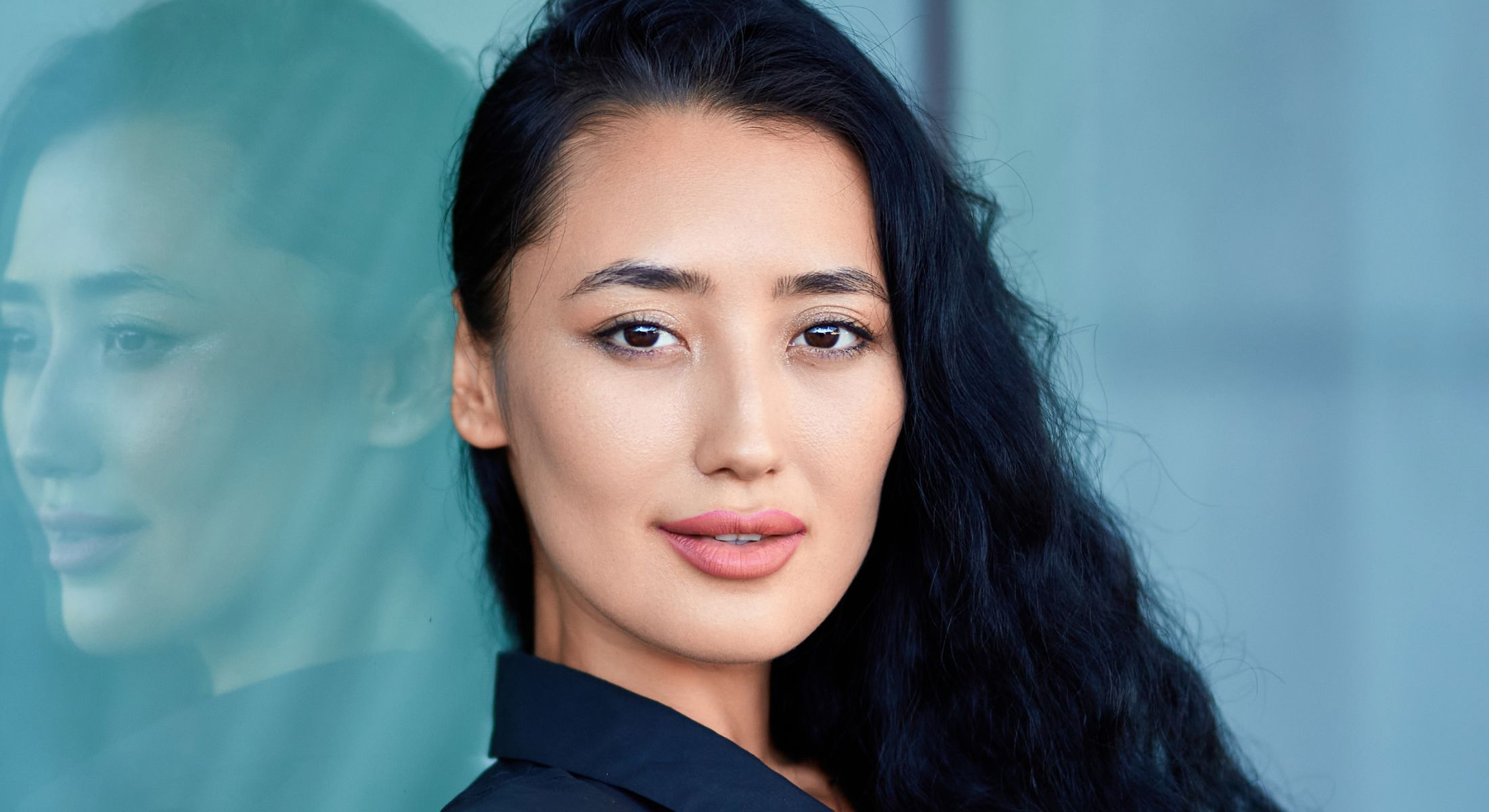 Woman with long black hair and soft smile.