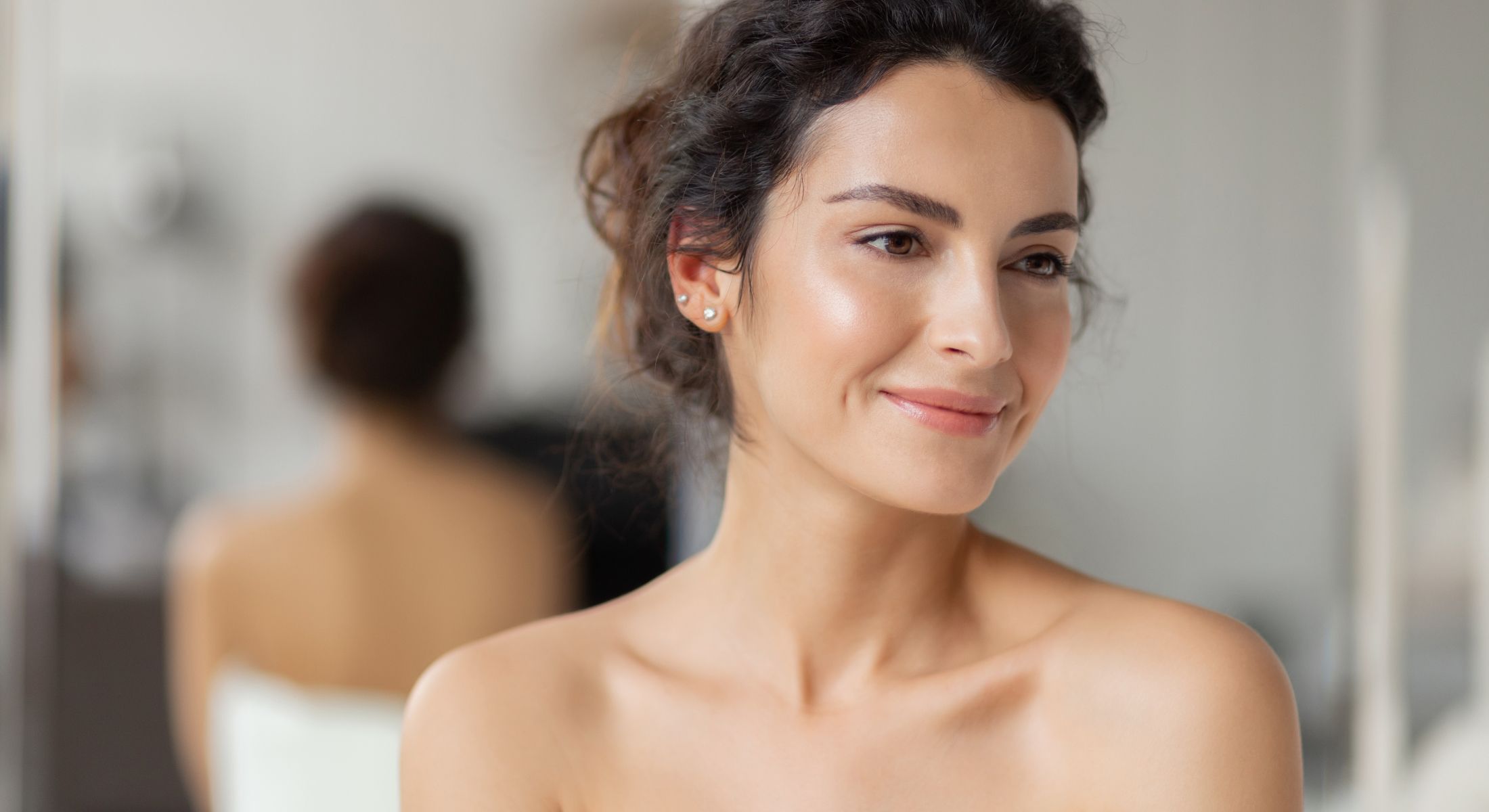 Smiling woman with curly hair in soft lighting.