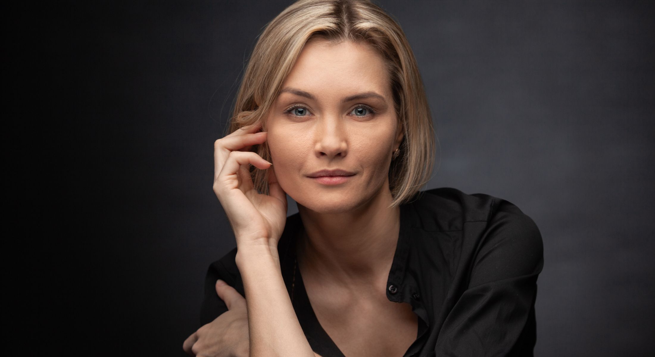 Woman with short blonde hair posing thoughtfully.